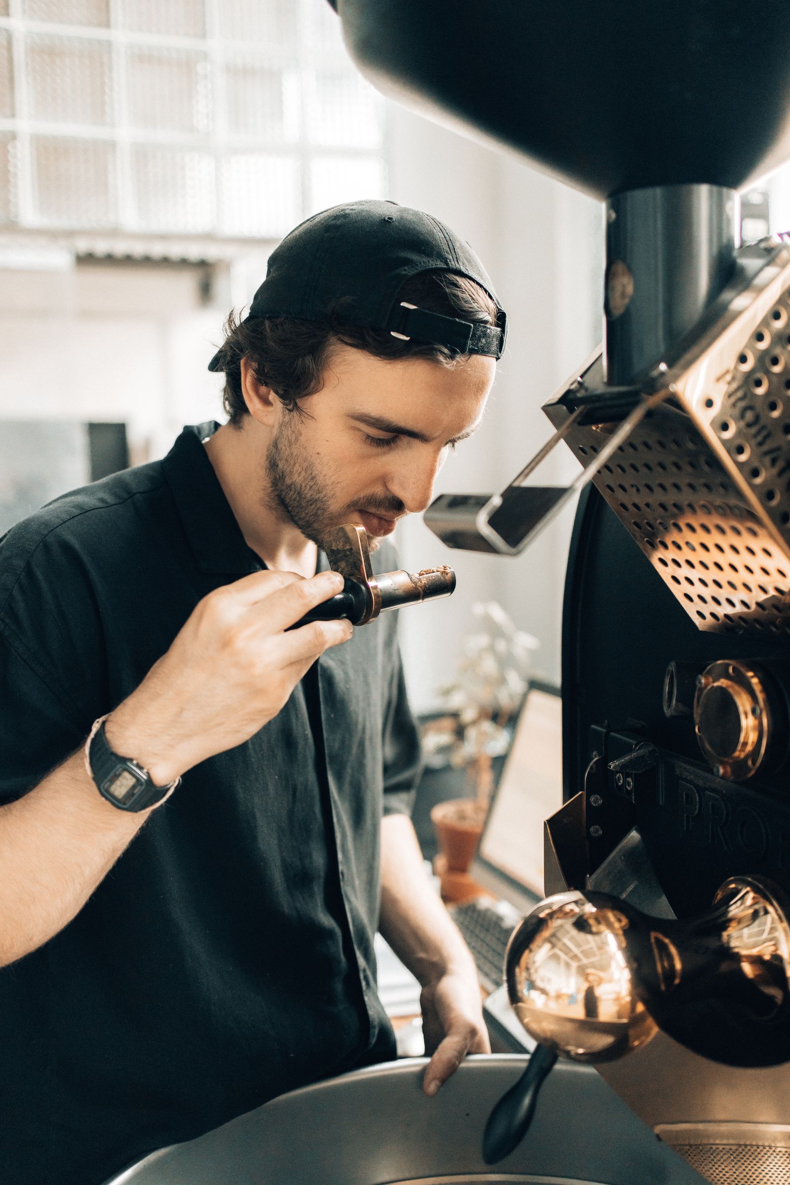 Roaster evaluating coffee beside a roasting machine